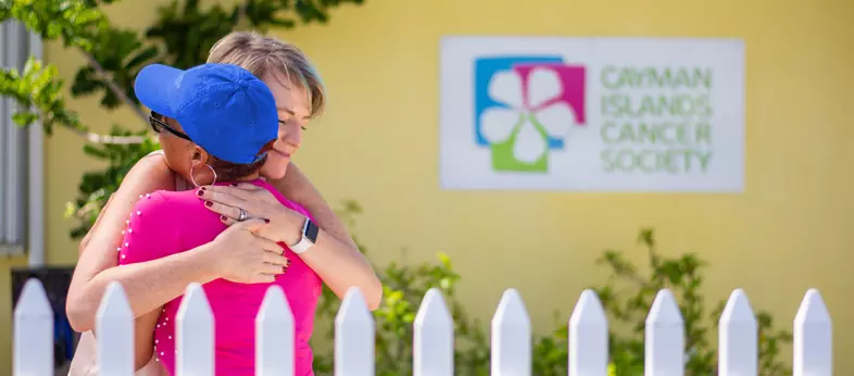 Two women embracing outside of the Cayman Islands Cancer Society Centre